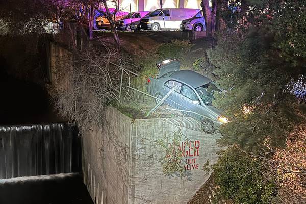 Police: chase ends with car dangling over 40-foot wall
